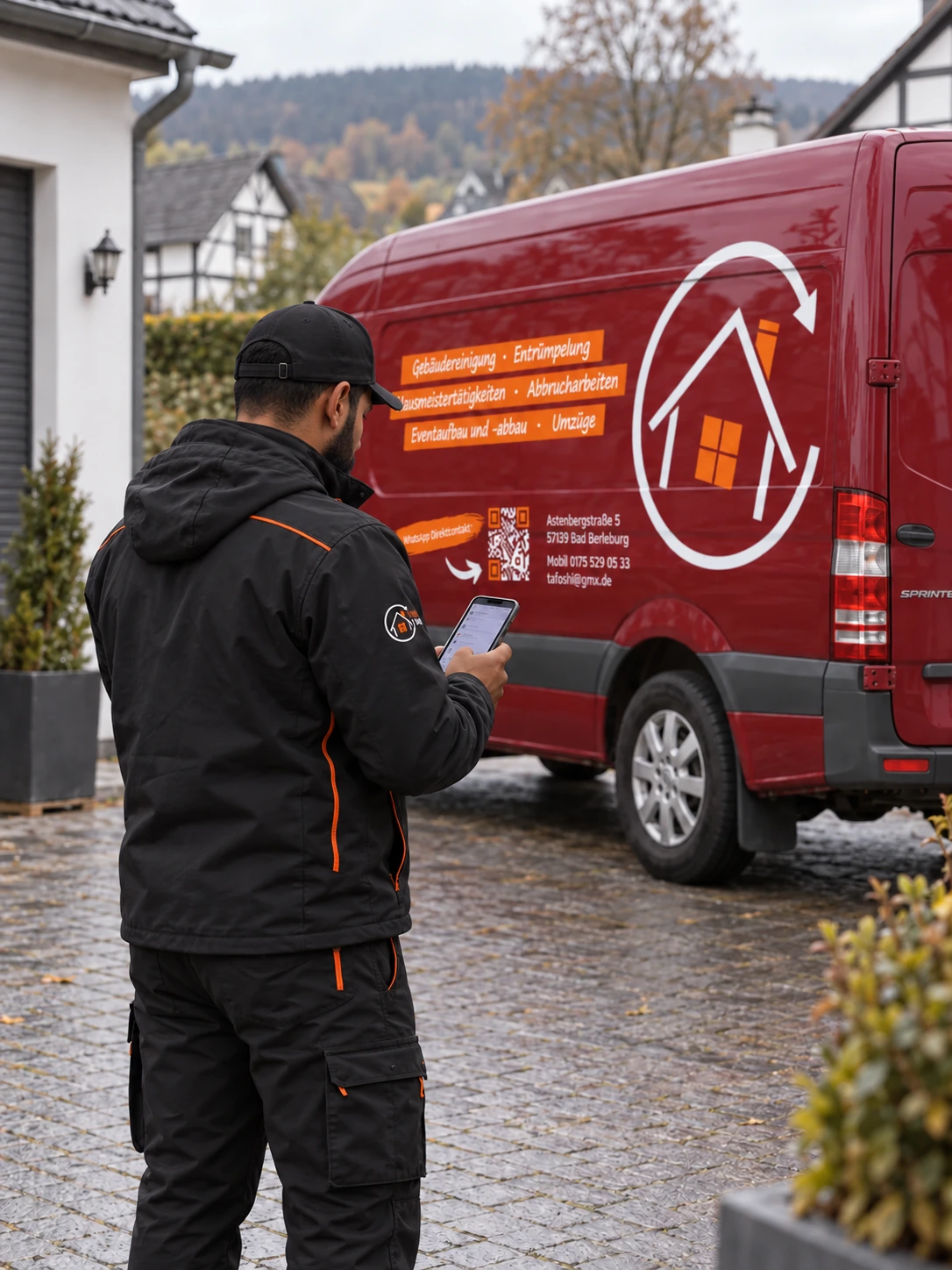 Tafoshi-Mitarbeiter mit Smartphone vor dem roten Firmentransporter